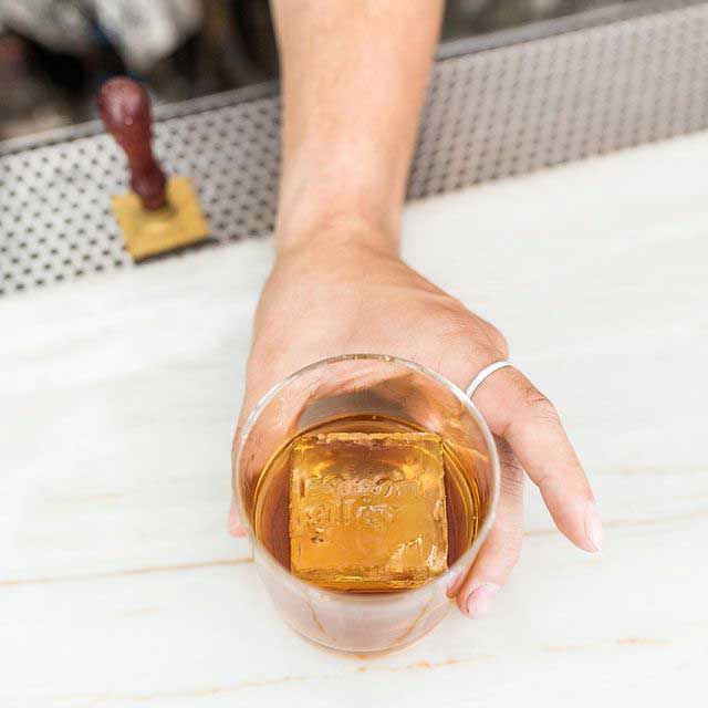 Image of an artisan ice cube stamped with the Saigon Alley logo.
