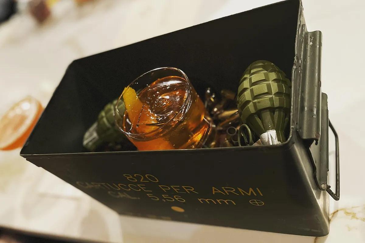 A cocktail being served in a box with hand grenades at Daniello’s
