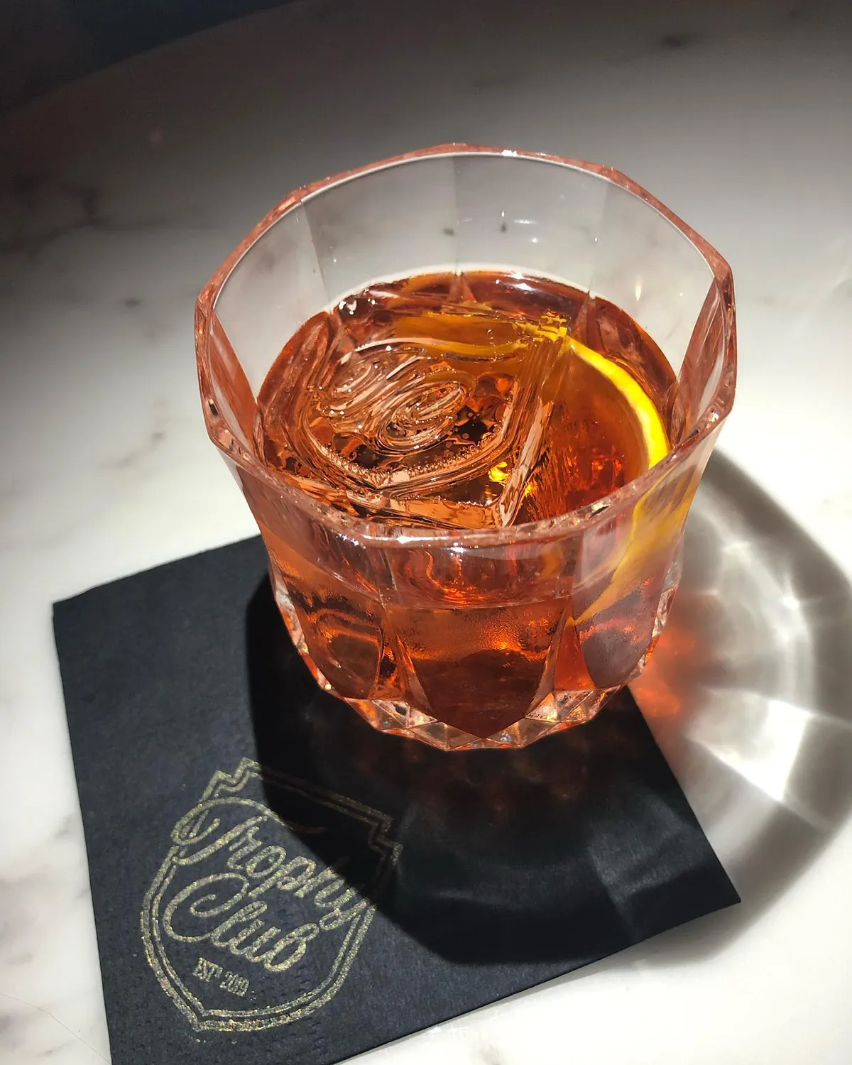 Image of a Trophy Club Old Fashioned cocktail with an oversized Trophy Club stamped Block Ice cube.